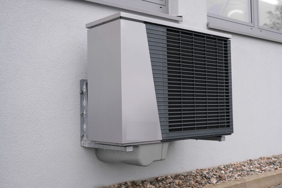 Buitenunit van een warmtepomp aan de gevel van een woning