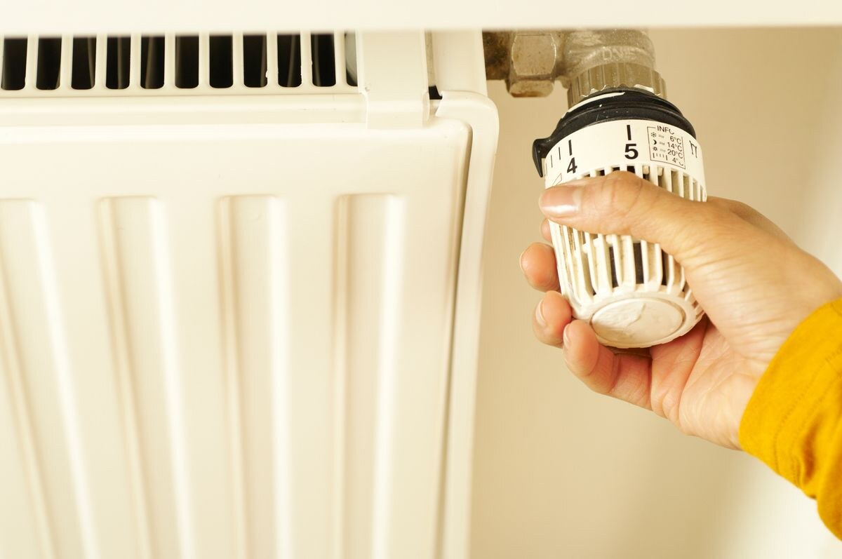 Monteur stelt de thermostaatknop van een radiator af